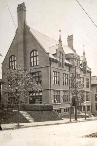 Black and white photograph of a building with many windows facing a street