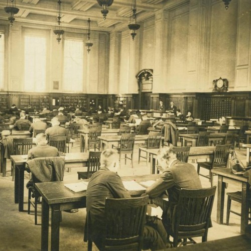 A black and white photo of a large room with rows of desks and chairs at John Hay Library with students studying