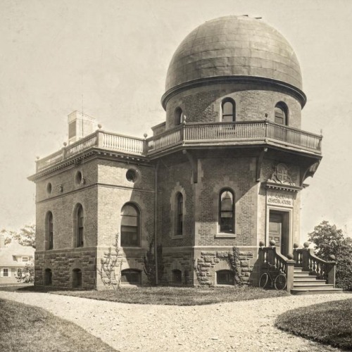 A black and white photo of an observatory building with a clear sky in the background