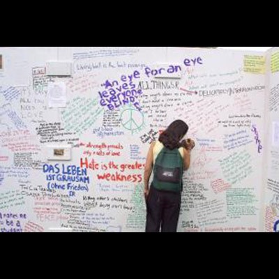 student drawing on a large memorial wall